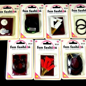 May include: Seven individual packs of earrings, each with a different design. The packs are all white with red stars and the words "fun fashion" in black. The earrings are made of various materials, including metal, plastic, and wood.