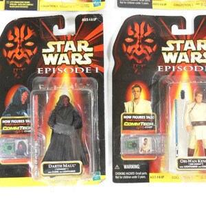 May include: Two Star Wars Episode I action figures in their original packaging. The figures are Darth Maul and Obi-Wan Kenobi. The packaging features the Star Wars logo and the words "Now figures talk! CommTech Chip".
