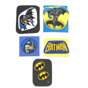 Pode incluir: Cinco patches para passar a ferro com o Batman. Os patches estão em fundos de cores diferentes, incluindo azul, amarelo e preto. Os patches apresentam o Batman em diferentes poses, incluindo voando, em pé e o logotipo do Batman.