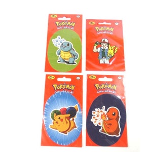 May include: Four colorful Pokemon stickers featuring different characters. The stickers are on a white background. The stickers are round and have a white border. The stickers feature the characters Squirtle, Pikachu, Charmander, and Bulbasaur.