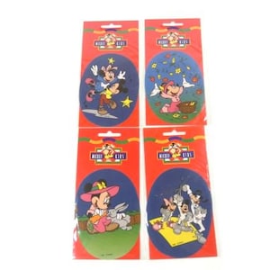 Op de afbeelding: Vier pakjes Mickey Kids stickers met verschillende scènes met Mickey Mouse, Minnie Mouse, Donald Duck en Goofy. Elk pakje heeft een rode achtergrond met de woorden "Mickey Kids" in wit.