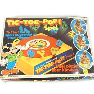 May include: A Mickey Mouse Tic-Toc-Pop! game box with a colourful design. The box features Mickey Mouse, Donald Duck, and a spinning game board with numbers. The text on the box reads "Tic-Toc-Pop! Spiel" and "Hall Disney Mickey Mouse Tic-Toc-Pop! Game".