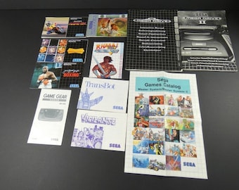 May include: A collection of Sega video game manuals and a game catalogue. The manuals include titles such as RHAMY, Boxing, TransBot, Vigilante, and Game Gear. The catalogue features a grid of game screenshots and the text "Sega Games Catalog Master System/Master System II".