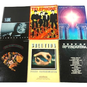 May include: A collection of six cassette tapes with album covers featuring various artists and bands, including Sade, Telephone, Earth Wind & Fire, The Secret Garden, Solution, and Best of Spyrogyra.