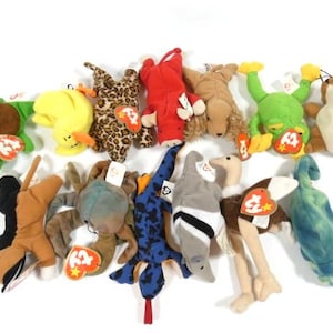 May include: A collection of 13 colorful beanie baby toys, including a turtle, a giraffe, a frog, a squirrel, a crab, an ostrich, a penguin, and a dolphin. Each toy has a red tag with the word "Ty" on it.