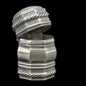 May include: A silver hexagonal box with a hinged lid. The lid has a rope-like design around the edge. The box is closed and the lid is open.