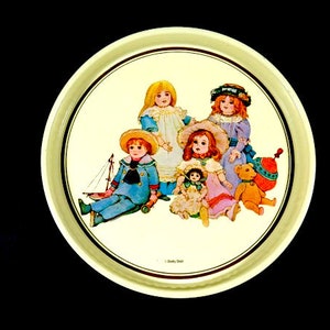 Puede incluir: Una bandeja redonda de metal de color crema con una ilustración colorida de cinco niños jugando con juguetes. Los niños están vestidos con ropa vintage y están rodeados de un velero, un oso de peluche y una peonza.