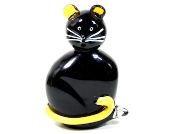 May include: A black glass cat figurine with yellow ears and tail. The cat has white eyes and whiskers.