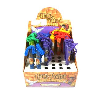Peut inclure: Un présentoir de stylos à thème Harry Potter avec des cordons colorés attachés. Les stylos sont dans un présentoir en plastique transparent avec un logo Harry Potter et une image d'un sorcier.