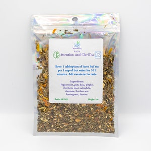 May include: A clear, resealable bag filled with loose leaf tea. The label reads "Attention and ClariTea" and lists ingredients like peppermint and gingko. The bag weighs 2oz and has a batch date of 08/2023.
