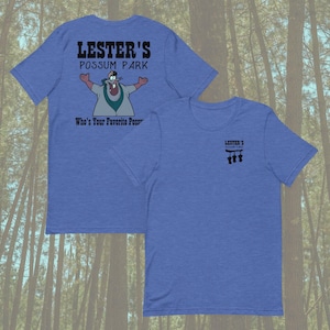May include: Two blue t-shirts. One displays "LESTER'S POSSUM PARK" with a cartoon possum and "Who's Your Favorite Poss". The other shirt has "LESTER'S POSSUM PARK" with three possums.