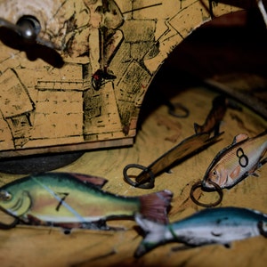 May include: Close-up of a vintage toy with a yellow and brown painted background. The toy features several fish with numbers 7 and 8, and a winding key. The fish have metal rings attached.