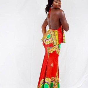May include: A red and green maxi dress with a halter top and a fitted skirt. The dress features a colourful African print pattern.