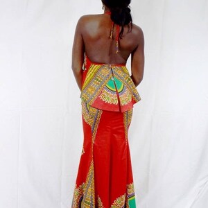 May include: A red maxi dress with a colourful patterned skirt and a halter top. The dress has a fitted bodice and a flowing skirt.