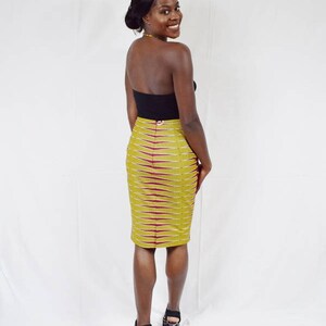 Puede incluir: Una mujer con un top negro sin tirantes y una falda l&aacute;piz de estampado amarillo y burdeos. Lleva tacones altos negros y tiene el pelo recogido hacia atr&aacute;s.