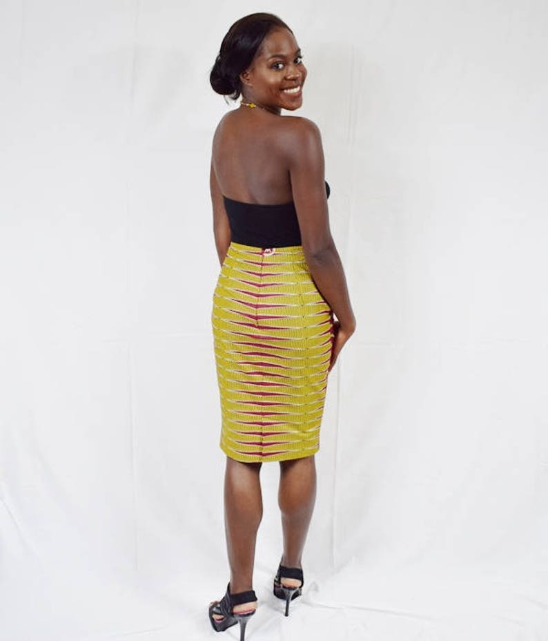 Puede incluir: Una mujer con un top negro sin tirantes y una falda l&aacute;piz de estampado amarillo y burdeos. Lleva tacones altos negros y tiene el pelo recogido hacia atr&aacute;s.