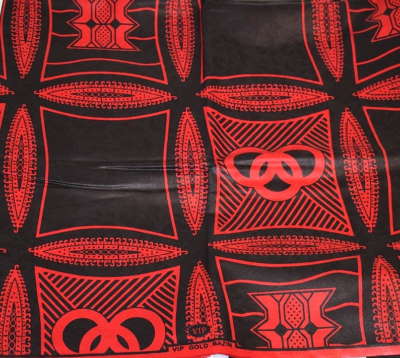 May include: Red and black fabric with a repeating pattern of interlocking circles and geometric shapes. The fabric has the text "VIP GOLD BAZIN" printed on it.