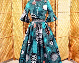 May include: A teal and black patterned skirt and matching crop top with bell sleeves. The skirt has a large circle pattern with white, black, and orange accents.