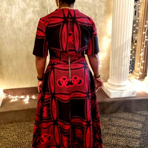 May include: A black and red patterned dress with a short-sleeved top and a long skirt. The skirt has a geometric design with a large circle in the center.