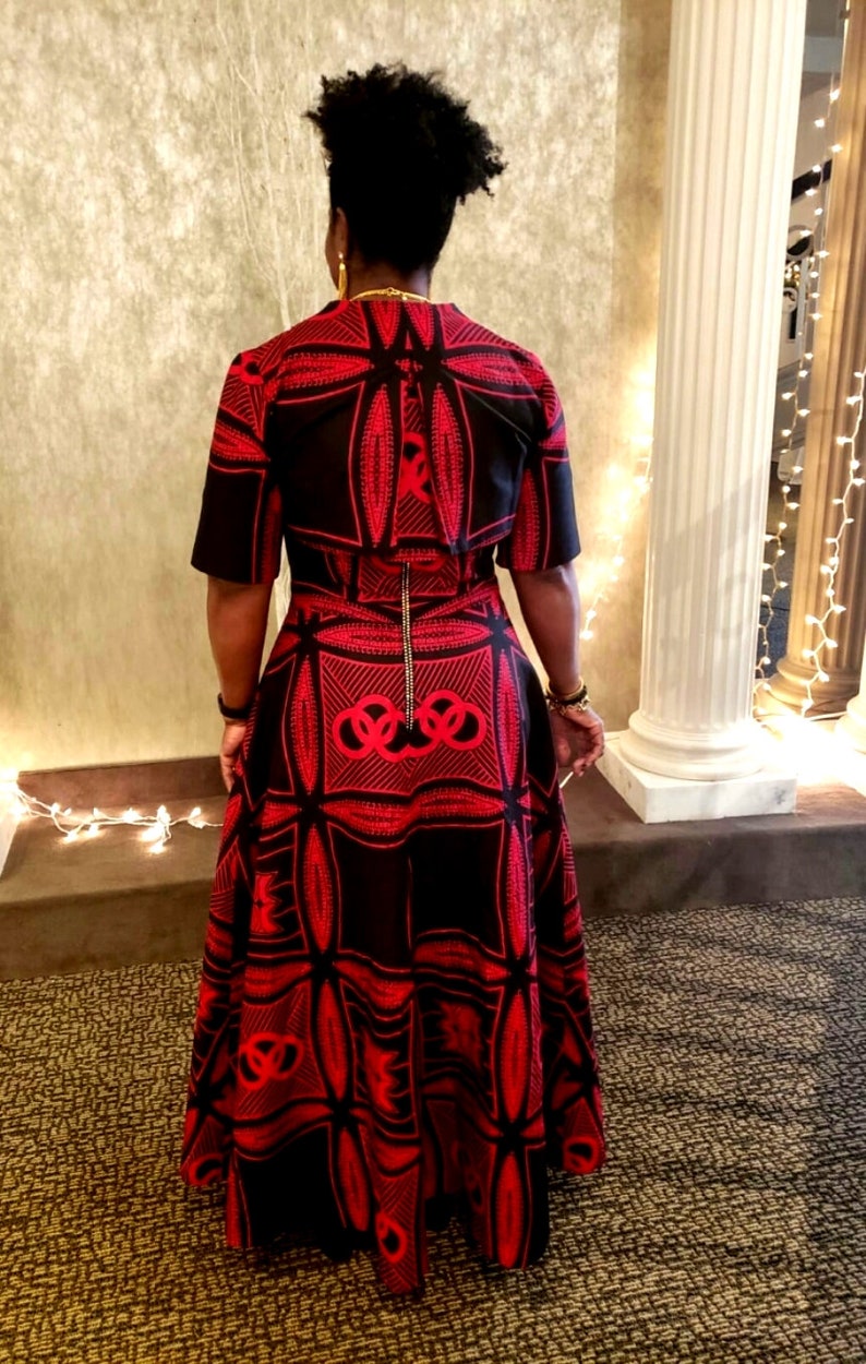 May include: A black and red patterned dress with a short-sleeved top and a long skirt. The skirt has a geometric design with a large circle in the center.