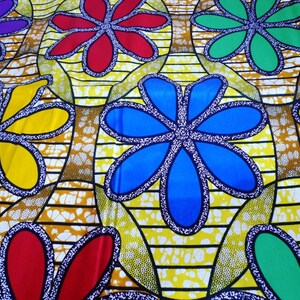 May include: A yellow fabric with a repeating pattern of colorful flowers. The flowers are outlined in black and have a white dotted pattern inside. The flowers are in shades of red, blue, green, and yellow.