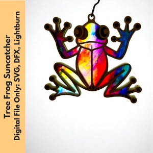 Peut inclure: Un capteur de soleil en forme de grenouille arboricole aux couleurs de l'arc-en-ciel. La grenouille est faite d'un matériau marron foncé avec un intérieur multicolore. Le texte sur le côté gauche indique "Tree Frog Suncatcher Digital File Only: SVG, DFX, Lightburn."
