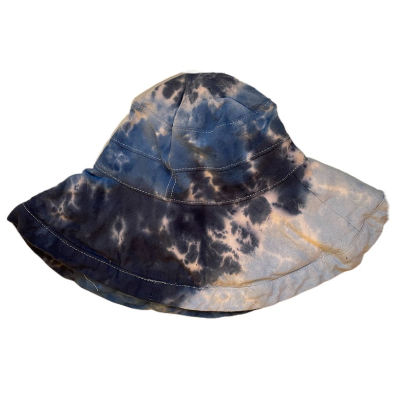 May include: A blue and white tie-dye bucket hat. The hat is made of a soft, lightweight fabric and has a wide brim.