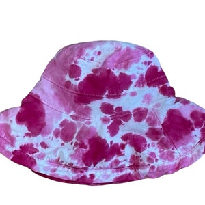 May include: A pink and white tie-dye bucket hat. The hat has a wide brim and is made of a soft, comfortable fabric.