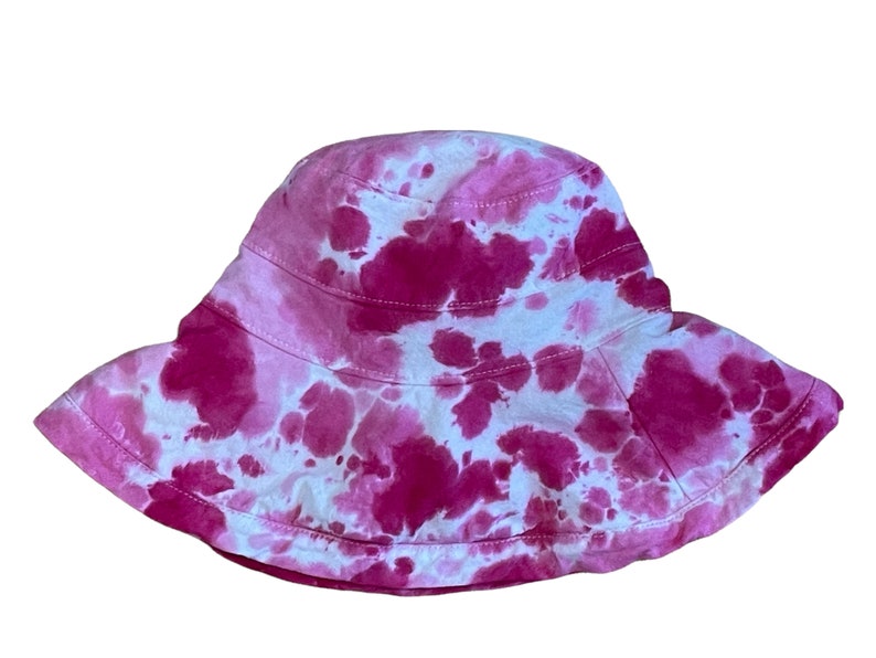 May include: A pink and white tie-dye bucket hat. The hat has a wide brim and is made of a soft, comfortable fabric.