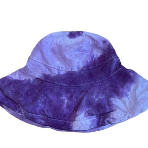 May include: A purple and white tie-dye bucket hat with a wide brim.