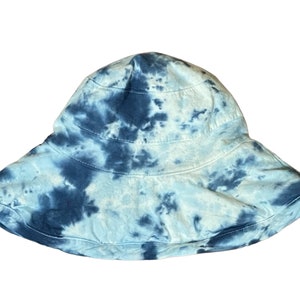 May include: A blue and white tie-dye bucket hat. The hat has a wide brim and is made of a soft, comfortable fabric.