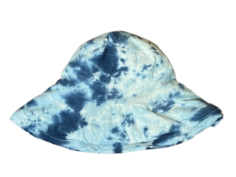 May include: A blue and white tie-dye bucket hat. The hat has a wide brim and is made of a soft, comfortable fabric.