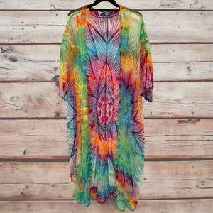 May include: A rainbow tie-dye crochet kimono with a floral design. The kimono is sheer and has a scalloped hem.