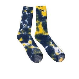 May include: A pair of blue and yellow tie-dye socks with a black Nike swoosh logo on each sock.
