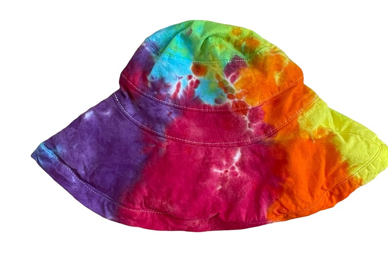 May include: A colourful tie-dye bucket hat with a wide brim. The hat is made of a soft, comfortable fabric and features a variety of colours, including purple, pink, orange, yellow, and green.