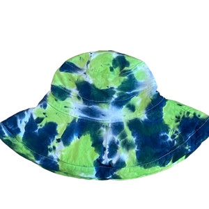 May include: A green and blue tie-dye bucket hat. The hat has a wide brim and is made of a soft, comfortable fabric.