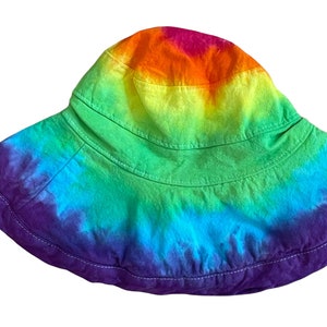 May include: A rainbow tie-dye bucket hat with a wide brim and a purple band around the bottom.