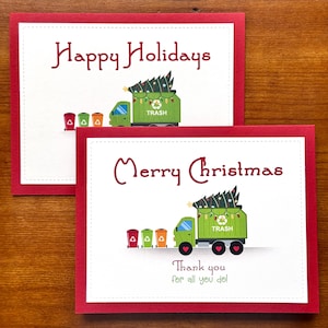 May include: Two Christmas cards featuring a green garbage truck with a Christmas tree on top. The top card says "Happy Holidays" and the bottom card says "Merry Christmas" and "Thank you for all you do!"