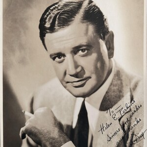 May include: Black and white vintage photograph of a man in a suit, tie, and collared shirt, holding a cigarette. The photograph is signed "Richard Day" with a handwritten message to "Helen E. Perkins."
