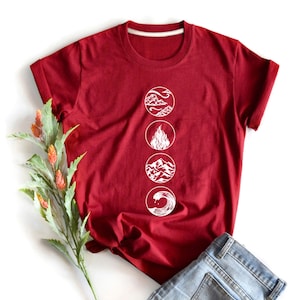 Puede incluir: Una camiseta roja con un gráfico blanco de cuatro círculos, cada uno con un elemento diferente: aire, fuego, tierra y agua.