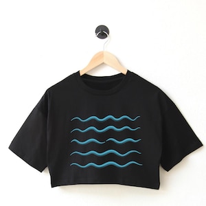 May include: Black cropped t-shirt with a blue wave design.