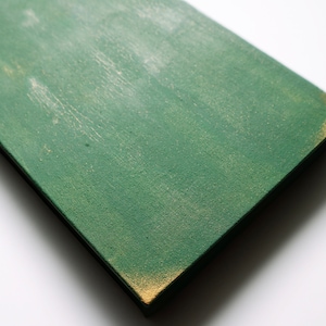 May include: A green wooden sign with a distressed finish and a gold edge. The sign is blank and ready to be painted or decorated.
