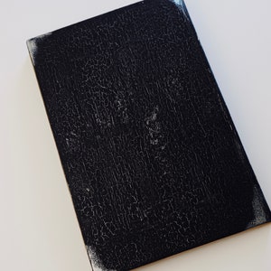 Puede incluir: Una superficie rectangular negra texturizada con un aspecto agrietado y envejecido.