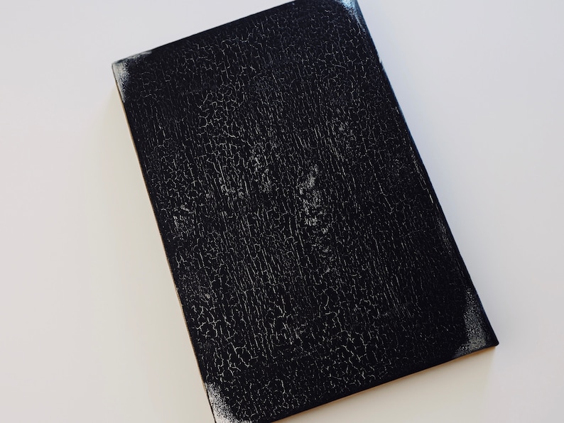 Puede incluir: Una superficie rectangular negra texturizada con un aspecto agrietado y envejecido.