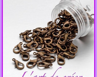 May include: A clear plastic jar with a metal lid spilling out a large quantity of small, antique gold-colored metal lobster claw clasps. The clasps are used for jewelry making.