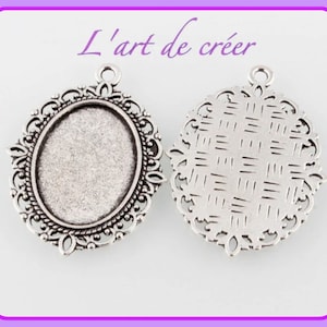Può includere: Ciondolo ovale argentato con un designo a filigrana decorativo. Il ciondolo ha una superficie liscia e piatta e un anello nella parte superiore per attaccare una catena o un cordino.