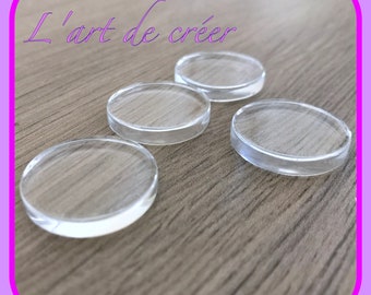 May include: Four clear round glass or plastic discs on a wood surface.