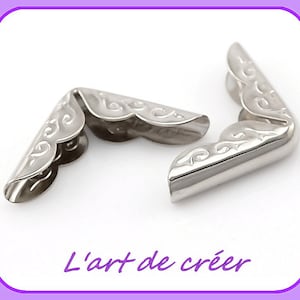 Puede incluir: Dos protectores de esquina de metal plateado con un borde decorativo festoneado. Los protectores están diseñados para proteger las esquinas de artículos de tela o cuero.