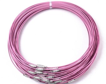 May include: A bundle of pink colored metal chain necklaces with silver clasps. The necklaces are coiled together in a circle.