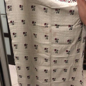 Peut inclure: Une nappe en lin blanche avec un motif r&eacute;p&eacute;t&eacute; de fleurs brod&eacute;es rouges et vertes. La nappe a une bordure de feuilles brod&eacute;es rouges et vertes.